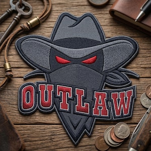 May include: Embroidered patch featuring a stylized outlaw design. The patch showcases a dark gray cowboy hat and mask with menacing red eyes. The word "OUTLAW" is embroidered in red with a white outline. The patch is on a wooden surface.