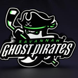 May include: A black and white illuminated sign featuring the Savannah Ghost Pirates logo. The logo depicts a pirate with a hockey stick, with the words "Savannah Ghost Pirates" in a stylized font. The sign has green accents and a black background.