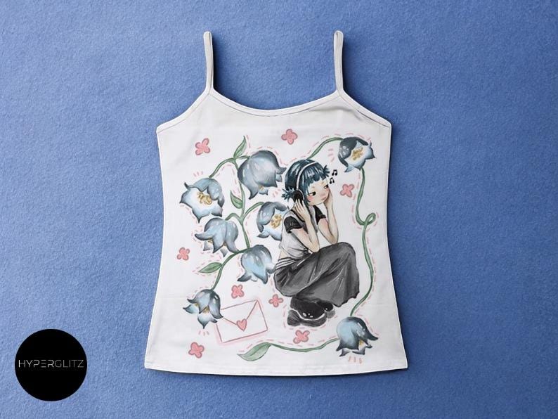 May include: White tank top with a floral illustration featuring a girl wearing headphones, surrounded by blue flowers and pink accents. The design includes a letter with a heart. The brand name "HYPERGLITZ" is on the bottom left.