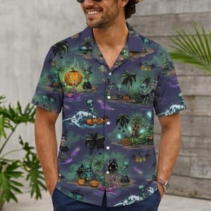 May include: A short-sleeve button-down shirt in a dark purple hue featuring an all-over print of green aliens, palm trees, pumpkins, and witch hats. The graphic pattern includes glowing light effects, flying saucers, and tropical island scenery.