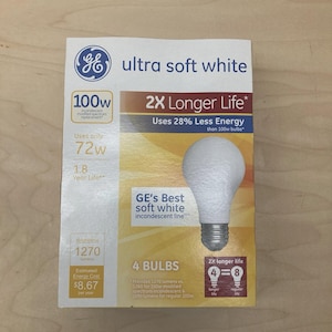 May include: A package of GE Ultra Soft White light bulbs. The box features the GE logo, bulb specifications, and the text "2X Longer Life." It states the bulbs use 72W and have a brightness of 1270 lumens. The box contains 4 bulbs.