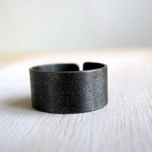 May include: A black metal ring with a textured finish.