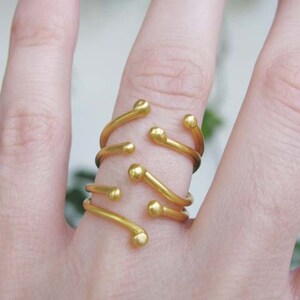 May include: A gold ring with multiple bands and small round accents. The ring is worn on a finger.