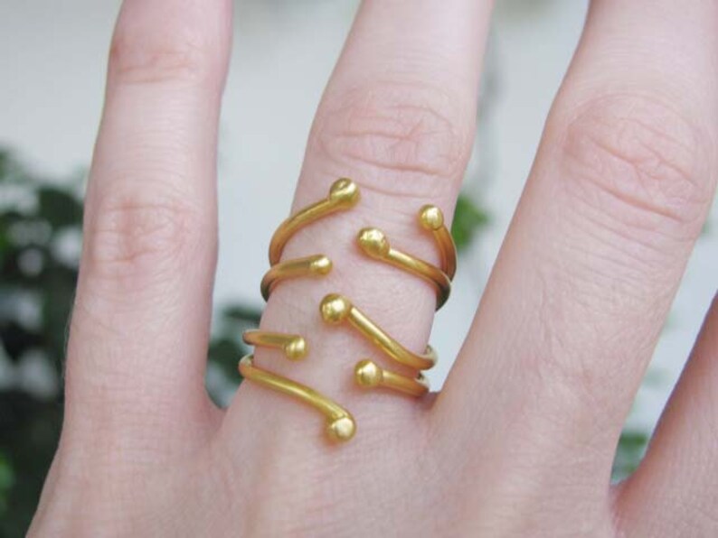 May include: A gold ring with multiple bands and small round accents. The ring is worn on a finger.