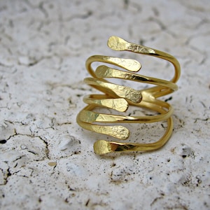 Peut inclure: Une bague en or avec un design unique et multicouche. La bague est composée de plusieurs fines bandes de métal qui sont torsadées et entrelacées pour créer un aspect texturé et organique.