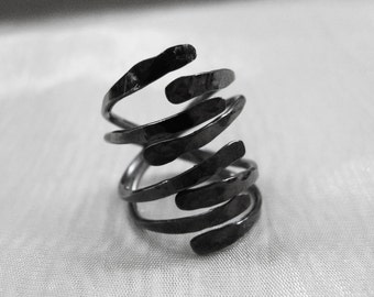 May include: A black metal ring with a unique, multi-layered design. The ring is made of several thin, curved pieces of metal that are intertwined to create a spiral effect.