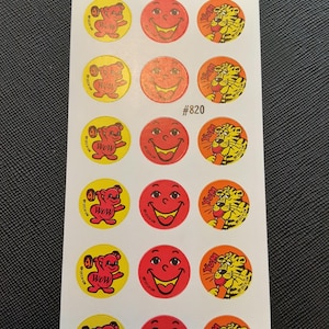 Puede incluir: Una hoja de pegatinas vintage con varios diseños. Las pegatinas incluyen una cara sonriente, un oso levantando pesas con la palabra "WOW" y un tigre con la palabra "Yum". Las pegatinas son redondas y tienen una estética retro.