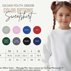 May include: White Gildan Youth 18000B sweatshirt with color options. The image shows a young girl wearing the sweatshirt. Color options include white, sport grey, safety pink, royal, red, maroon, forest green, dark heather, black, and navy. Sizes range from XS to XL.