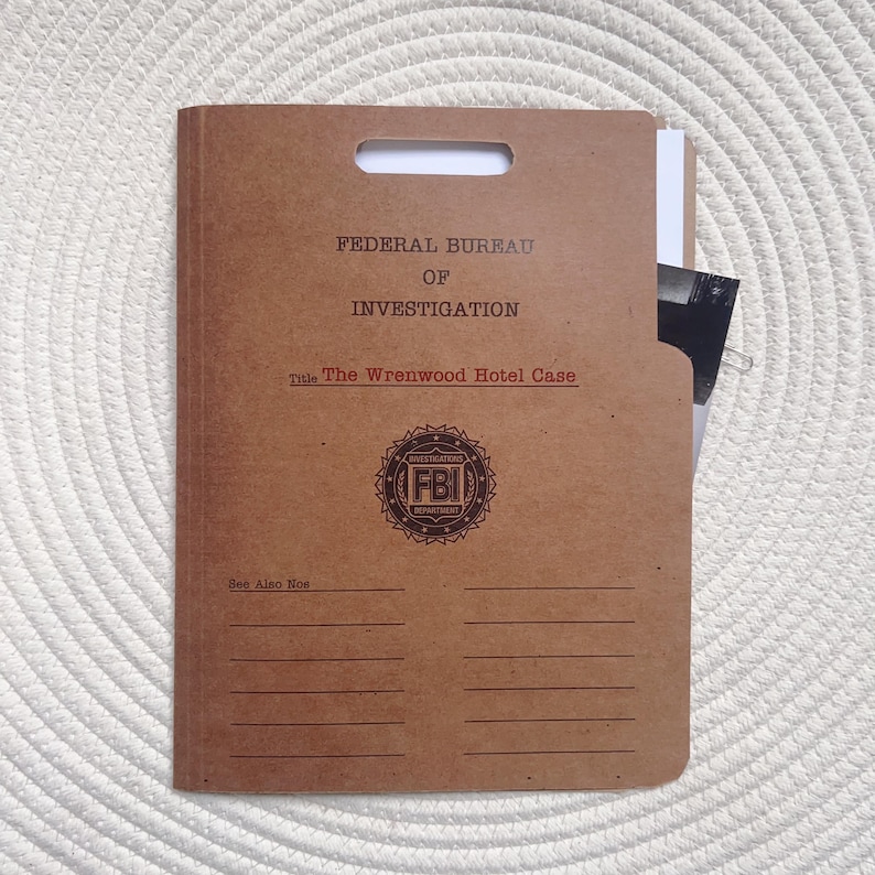 May include: A brown file folder with the text "FEDERAL BUREAU OF INVESTIGATION" and "The Wrenwood Hotel Case." The FBI seal is printed below the text. A white sheet of paper and a photograph are visible inside the folder.