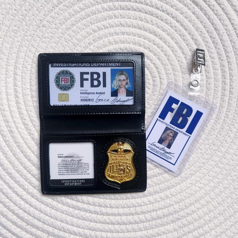 May include: Black leather FBI badge holder with a gold badge and an FBI identification card. The ID card displays the text "FBI" and "Investigations Department". A separate FBI ID card is also visible.