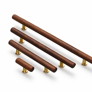 May include: A collection of five wooden cabinet pulls with brass-colored bases. The pulls are various lengths, with a dark brown, cylindrical design. The hardware is set against a white background.