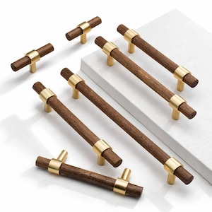 May include: A selection of wooden cabinet pulls with brass detailing. The pulls feature a cylindrical wooden handle with a brass ring and posts. The wood is dark brown, and the brass has a gold finish. Ideal for furniture.