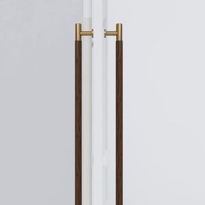 May include: A pair of door handles featuring a contemporary design. Each handle has a dark brown, cylindrical grip and is complemented by gold-toned hardware. They are mounted on a white door, offering a contrast of colours and textures.