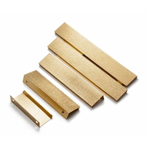 May include: A selection of brass-coloured cabinet pulls and handles in different sizes. The hardware has a brushed finish and a rectangular shape, with some pieces featuring a U-shaped design. The items are arranged on a white background.