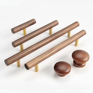 May include: A selection of wooden cabinet hardware, including pull handles and knobs. The pulls are cylindrical, made of dark brown wood, and have brass-coloured posts. The knobs are round and also made of dark brown wood.