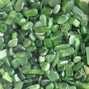 Peut inclure: Gros plan sur un tas de pierres de jade vertes polies. Les pierres, de formes variées, allant de rondes à rectangulaires, présentent différentes nuances de vert. Les surfaces lisses et réfléchissantes captent la lumière, créant un affichage vibrant.