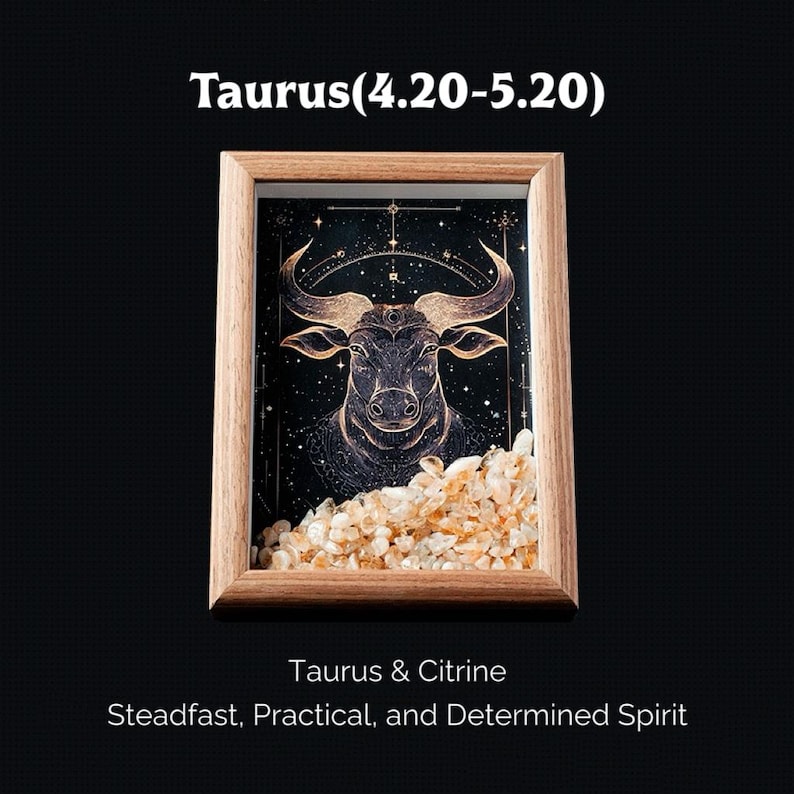 May include: A framed artwork featuring a detailed illustration of a bull, the Taurus zodiac sign, in gold and black. The frame is made of light-colored wood, and the bottom of the frame is filled with small, light-colored crystals. Text at the top reads "Taurus (4.20-5.20)".