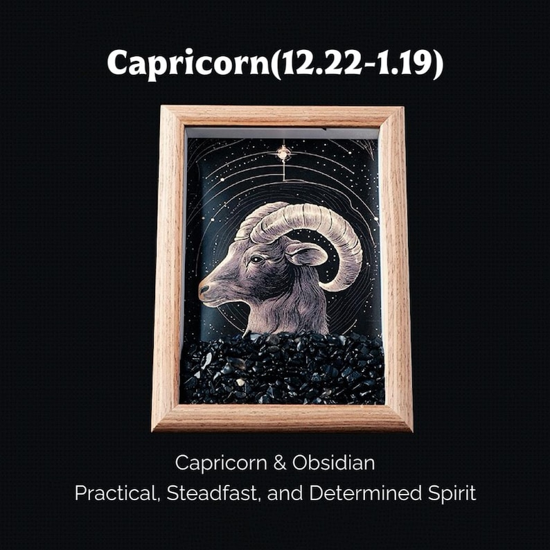 May include: A framed artwork featuring a Capricorn zodiac sign illustration. The image shows a detailed drawing of a goat's head with large curved horns, set against a starry background. The frame is made of light-colored wood, and the base is filled with black obsidian.
