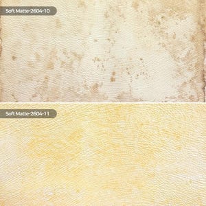 May include: Two rectangular swatches of textured material with a matte finish. The top swatch is off-white with brown mottled patches and the text Soft Matte-2604-10. The bottom swatch is pale yellow with light yellow patches and the text Soft Matte-2604-11.
