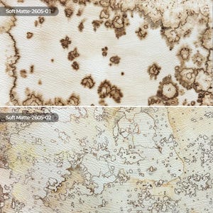 May include: Two rectangular swatches of textured material. The top swatch, labeled Soft Matte-2605-01, features a cream base with dark brown, irregular, organic-shaped spots. The bottom swatch, labeled Soft Matte-2605-02, has a light beige base with intricate, fine-lined brown patterns resembling topographical maps.