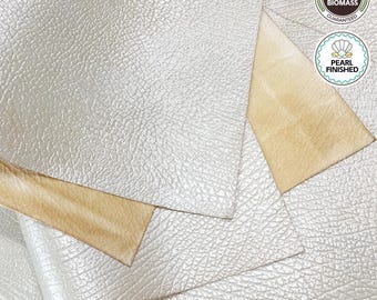 May include: Close-up of several sheets of pearlescent, textured material. The top layer is a light, shimmering color, while the underside is a warm beige. The image includes two circular seals with text: "Premium Quality 80UP Biomass Guaranteed" and "Pearl Finished."