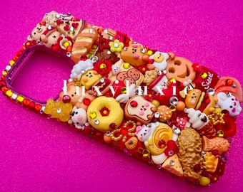 May include: A phone case decorated with a variety of colorful 3D charms, including donuts, bread, and cartoon animals. The case is covered in rhinestones and has a red and yellow color scheme.