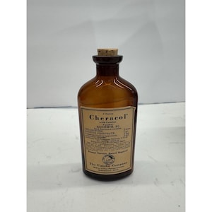 May include: An amber glass bottle with a cork stopper and a beige paper label. The label reads Cheracol with Codeine, The Upjohn Company, and lists ingredients including Chloroform and Codeine Phosphate, with a volume of 4 ounces printed clearly.