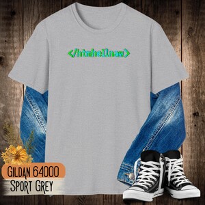 Op de afbeelding: Een lichtgrijs T-shirt met korte mouwen en de groene en blauwe tekst </htmhellnaw> op de borst. Het shirt is gelaagd over een blauw spijkerjack en gecombineerd met zwart-witte hoge sneakers, met een kleine gele bloem.