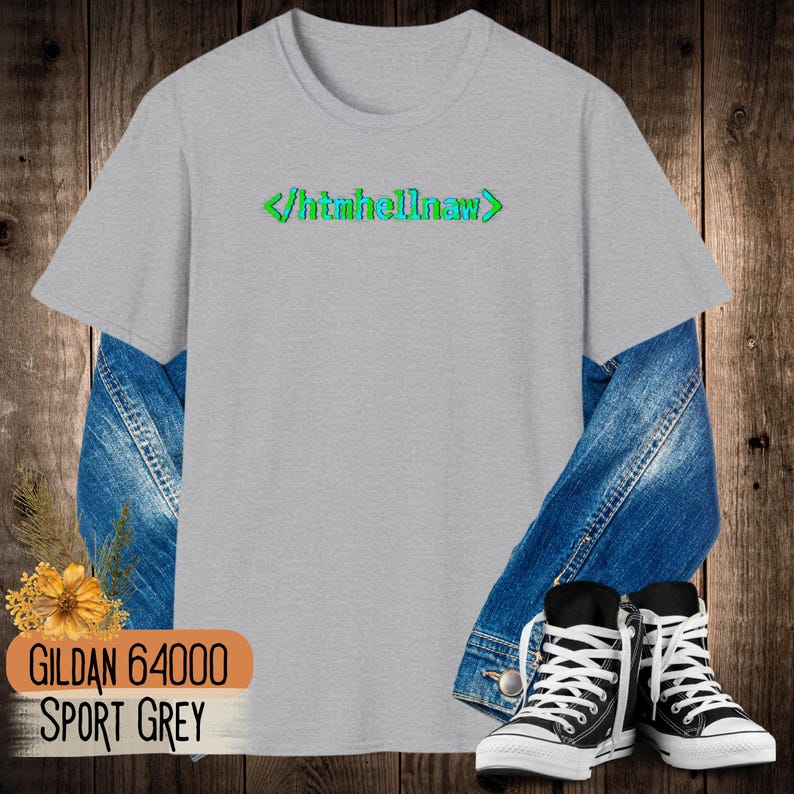 Op de afbeelding: Een lichtgrijs T-shirt met korte mouwen en de groene en blauwe tekst </htmhellnaw> op de borst. Het shirt is gelaagd over een blauw spijkerjack en gecombineerd met zwart-witte hoge sneakers, met een kleine gele bloem.