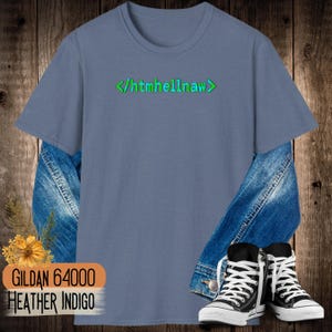 Op de afbeelding: Een heather indigo t-shirt met korte mouwen en de groene tekst </htmhellnaw> op de borst gedrukt. Het shirt is gelaagd over een blauw spijkerjack en gecombineerd met zwart-witte hoge sneakers, wat zorgt voor een casual alledaagse uitstraling.