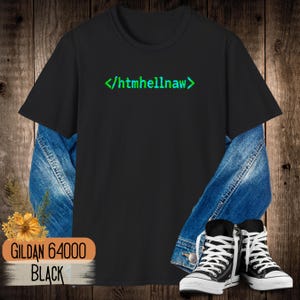 Op de afbeelding: Een zwart t-shirt met korte mouwen en de tekst "</htmhellnaw>" in een korrelig groen lettertype op de borst. Het shirt is gelaagd over een blauw spijkerjack en gecombineerd met zwart-witte hoge sneakers, met een label waarop "GILDAN 64000 BLACK" staat.