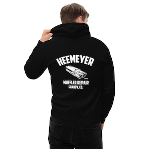May include: Black hooded sweatshirt featuring the white text "HEEMEYER" above a muffler graphic. Below the graphic is the text "MUFFLER REPAIR GRANBY, CO."