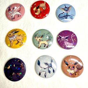 May include: Nine colorful round pinback buttons featuring various cartoon creatures. The buttons have a glossy finish and are in shades of pink, red, blue, yellow, green, purple, black, silver, and brown. Each button has a unique design.