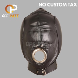 May include: Black leather hood with a large circular opening and a metal ring. The hood has eye openings and a strap with a buckle. The text "NO CUSTOM TAX" is at the top.
