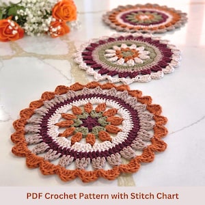 May include: Three handmade crochet doilies in shades of orange, burgundy, cream, and green. The doilies have a circular design with a scalloped edge. The text "PDF Crochet Pattern with Stitch Chart" is at the bottom of the image.