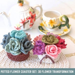 May include: Two crochet flower coasters in brown and white pots, with a teapot and teacup in the background. The coasters feature blue, gray, pink, and green flowers. The text at the bottom reads "POTTED FLOWER COASTER SET: 3D FLOWER TRANSFORMATION."