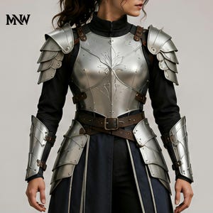 Peut inclure: Un ensemble d'armure en métal argenté poli comprenant un plastron avec des motifs floraux gravés, des épaulières superposées et des brassards. L'armure est fixée par des lanières en cuir marron et des boucles sur un vêtement noir à manches longues.