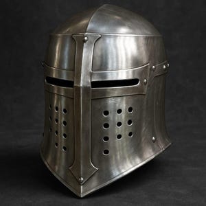 Può includere: Un elmo da cavaliere medievale color argento con un design a croce. L'elmo presenta fessure per gli occhi, fori di ventilazione e una costruzione rivettata. L'elmo è in metallo e ha una finitura lucida.