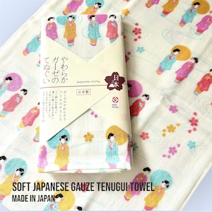 Może przedstawiać: Miękki japoński ręcznik tenugui z gazy z powtarzającym się wzorem postaci w kolorowych kimonach. Ręcznik jest biały z różowymi, żółtymi i niebieskimi akcentami. Na opakowaniu widnieje napis "Japanese style" i "Made in Japan."