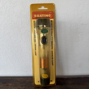 May include: A yellow and clear flashlight in a package. The package reads "BOATING ESSENTIALS" and "JUST SHAKE - NO BATTERY NEEDED". The flashlight has a black base and a copper-colored coil. The text "WATER PROOF" is also visible.