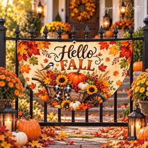 Könnte beinhalten: Ein halbkreisförmiges Banner mit dem Text Hello Fall, verziert mit Herbstblättern, Sonnenblumen, Kürbissen, einem kleinen Vogel und einem Holzwagen mit einer schwarz-weiß karierten Schleife, aufgehängt an einem schwarzen Metallzaun.