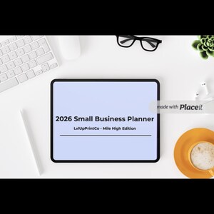 May include: A digital tablet displaying the text "2026 Small Business Planner" with the subtitle "LvUpPrintCo - Mile High Edition." The tablet is surrounded by a keyboard, mouse, glasses, a succulent, a stylus, and a cup of coffee.