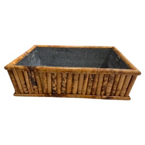 May include: Rectangular planter box with a bamboo exterior and a galvanized metal interior. The bamboo is a light brown color with darker brown accents. The planter is designed for outdoor or indoor use.