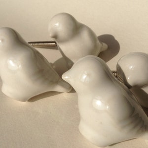 May include: Four white ceramic bird-shaped drawer pulls with silver metal screws.