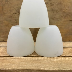 May include: Three white frosted glass lampshades stacked on top of each other.