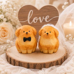 May include: Two carved wooden dog figurines standing on a circular wood slice. The left dog wears a black bow tie, and the right dog wears a white lace veil. Behind them is a heart-shaped wooden sign with the word love written in white script.
