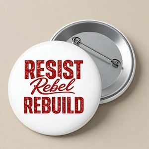 May include: White button with the words "RESIST Rebel REBUILD" in distressed red lettering. The button has a silver pin back. The design is centered on the white surface.