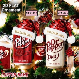 May include: Two 2D flat ornaments shaped like soda cans, one red and one white, each wearing a red and white Santa hat. The cans feature the Dr Pepper logo, the text 'WILLIAM 2026', and '12 FL OZ (355 ml)'. The ornaments are labeled 'STYLE 1' and 'STYLE 2'.