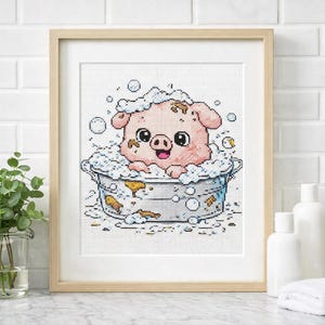 May include: Cross-stitch art of a pink pig taking a bath in a metal tub filled with bubbles. The pig has a happy expression and is covered in soap suds. The artwork is framed in a light wood frame.