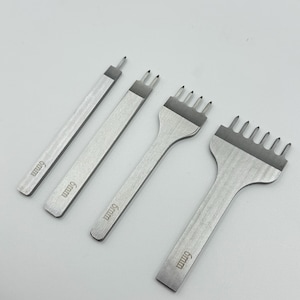 May include: Four silver leathercraft tools with the text "6mm" etched on each. The tools include a single-prong, two-prong, three-prong, and six-prong stitching chisel. The tools are arranged on a white surface.